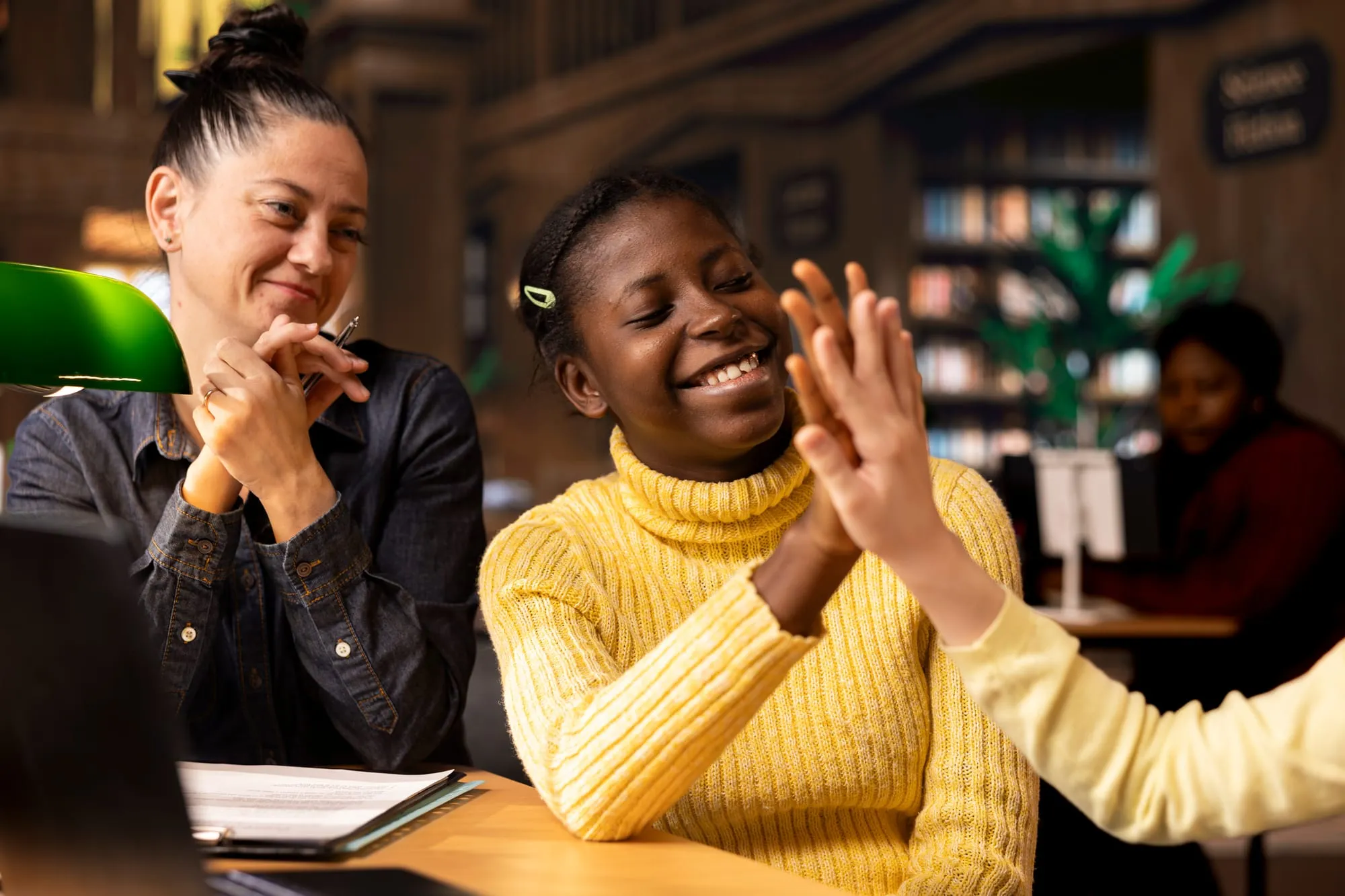 A mentor applauding a student in a library